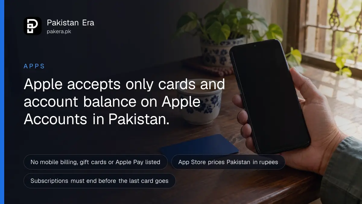 A hand holding a phone with its screen off beside a bank card on a wooden table in Karachi