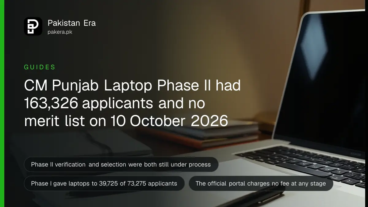 A closed silver laptop, a stack of university notebooks and a pen on a dark wooden study desk