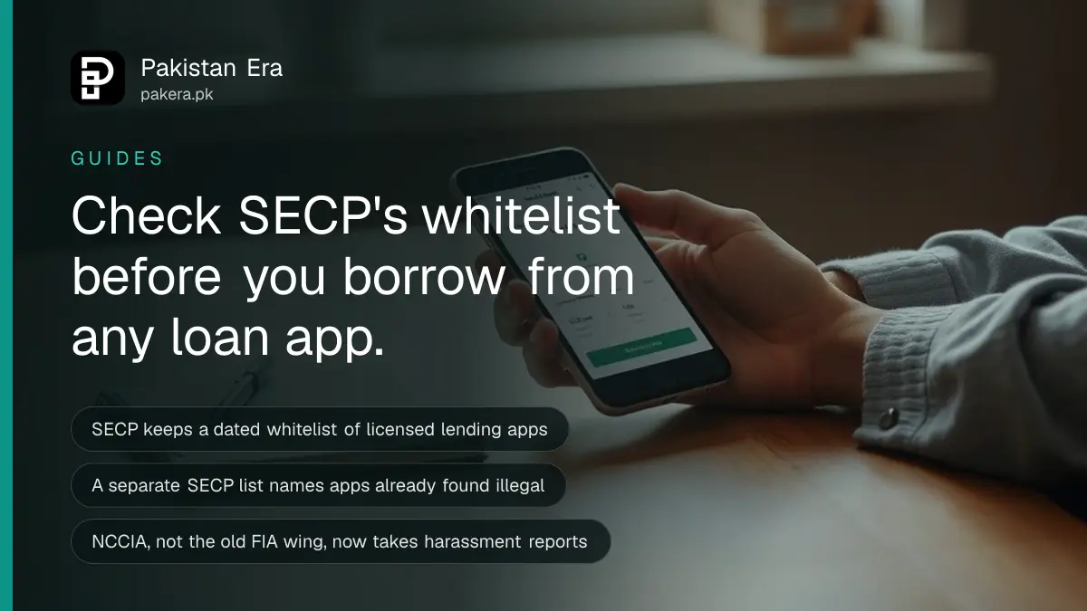 A person checking a loan app on a smartphone at a kitchen table with a notebook and pen nearby
