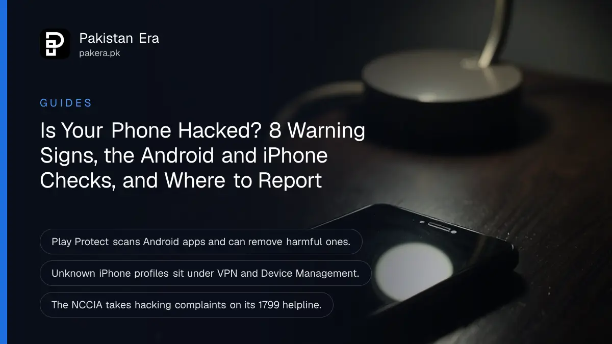 A smartphone lying face up on a dark wooden desk at night with its screen dark, a desk lamp glowing softly beside it