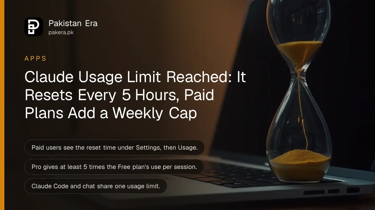 A glass hourglass with falling sand beside an open silver laptop on a wooden study desk in warm lamp light
