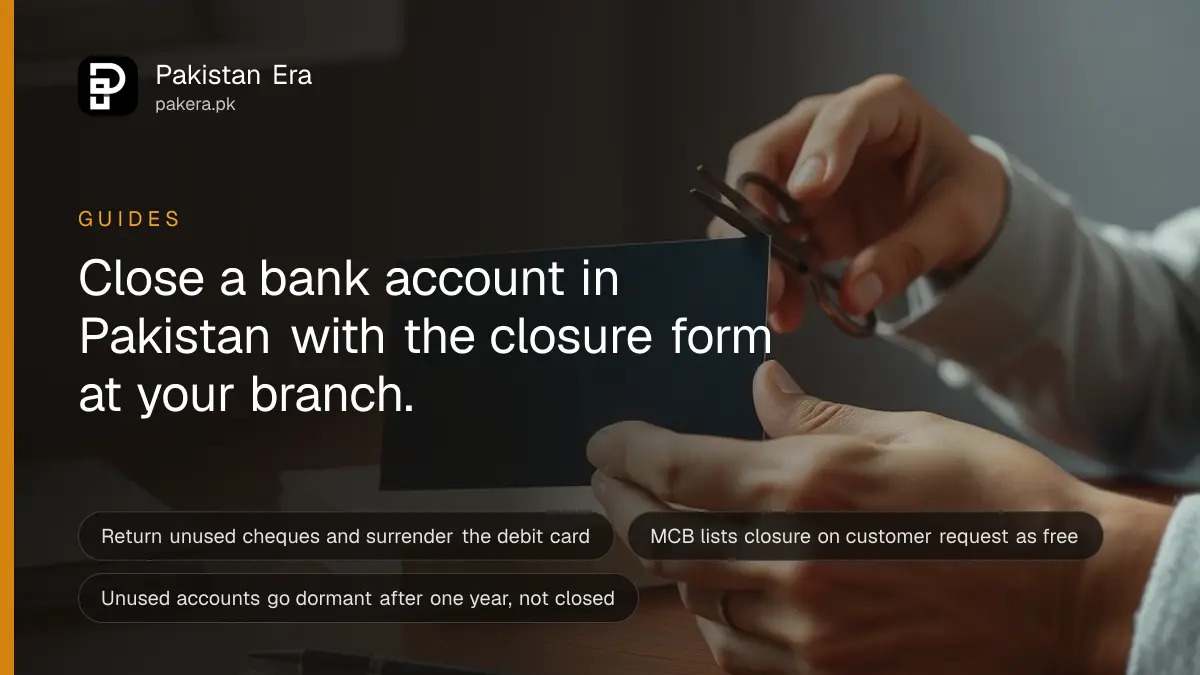 Hands holding a pair of scissors over a plain blank plastic card on a wooden desk