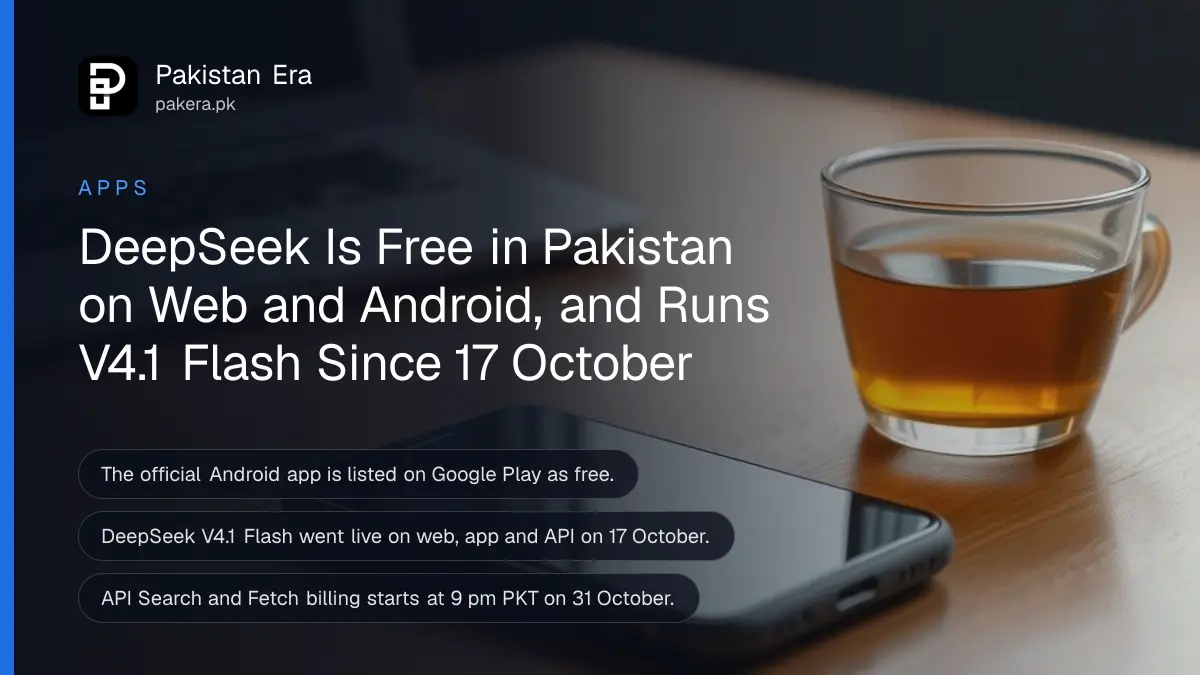 A smartphone lying face up on a wooden desk with its screen dark, beside an open plain silver laptop and a cup of tea
