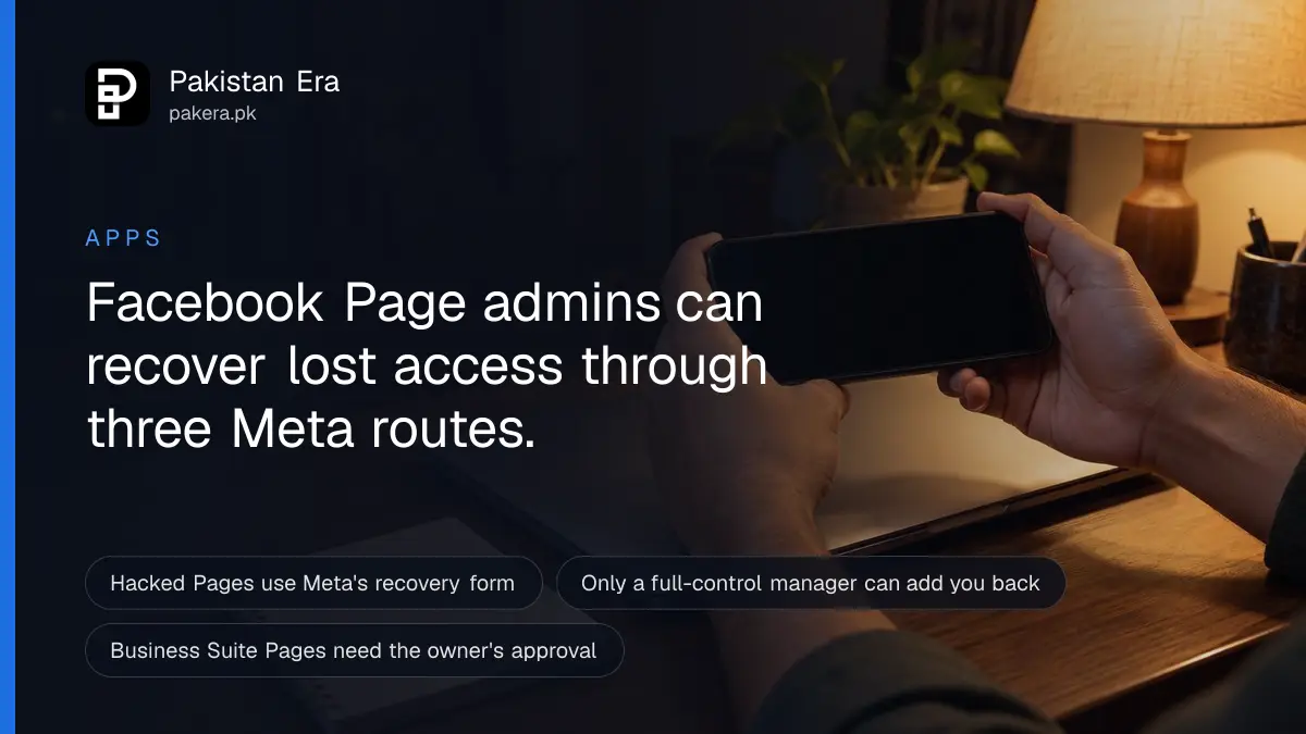Hands holding a phone with its screen dark above a closed laptop on a desk at night