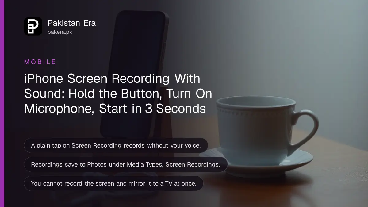 A smartphone standing in a small desk stand beside a pair of white earphones and a cup of tea on a wooden table