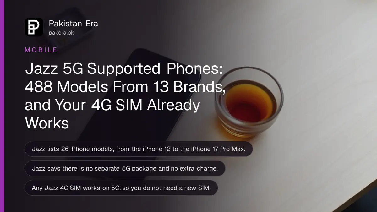 A smartphone lying face up on a wooden desk with its screen dark, beside a small SIM tray and a cup of tea