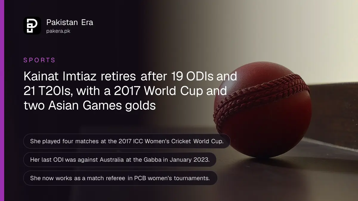 A new red cricket ball on a dark wooden table against a plain cream wall in soft daylight