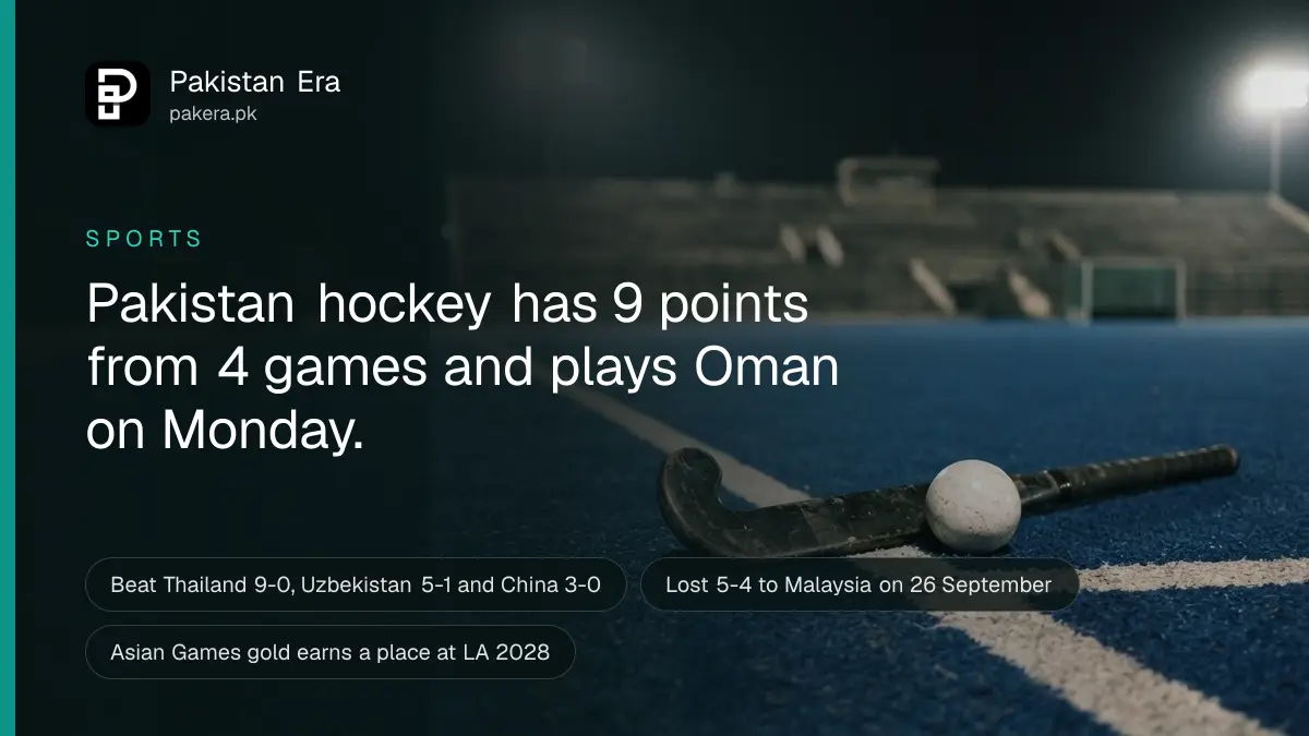 A hockey stick and a white ball on blue artificial turf under stadium floodlights at night