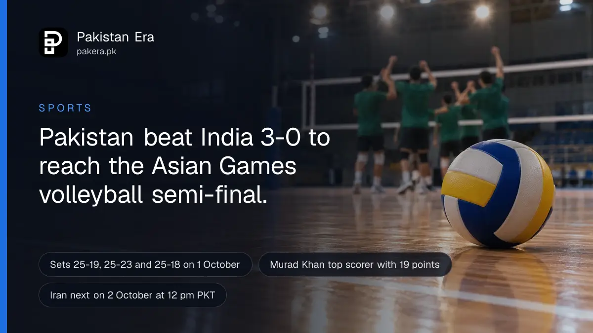 A white and blue volleyball resting on a polished wooden indoor court floor beside the net post under bright hall lights