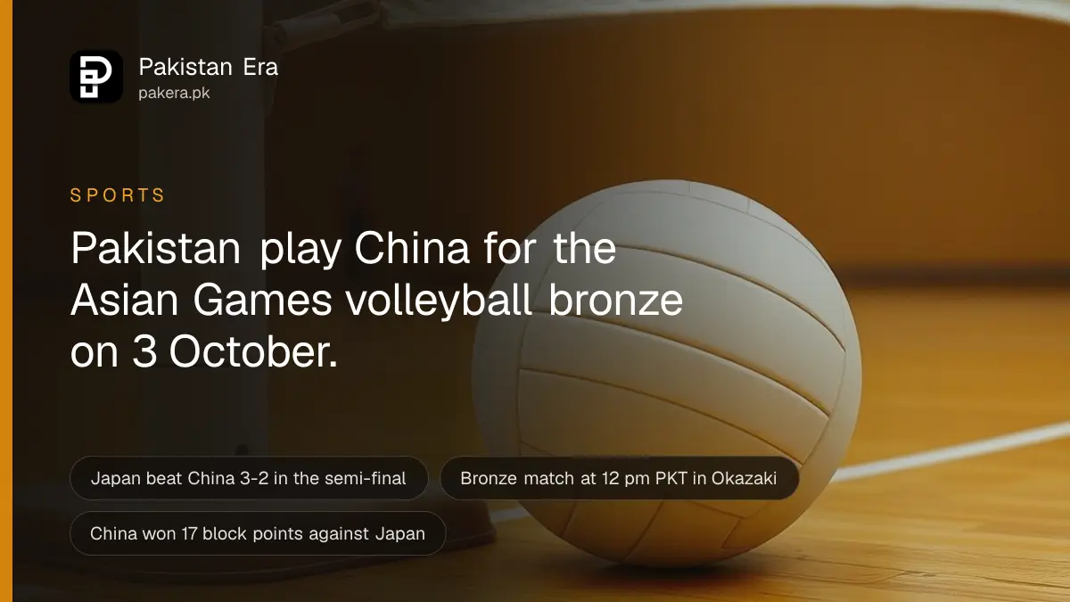 A plain white volleyball resting on the polished wooden floor of an empty indoor court beside a net post under bright hall lights
