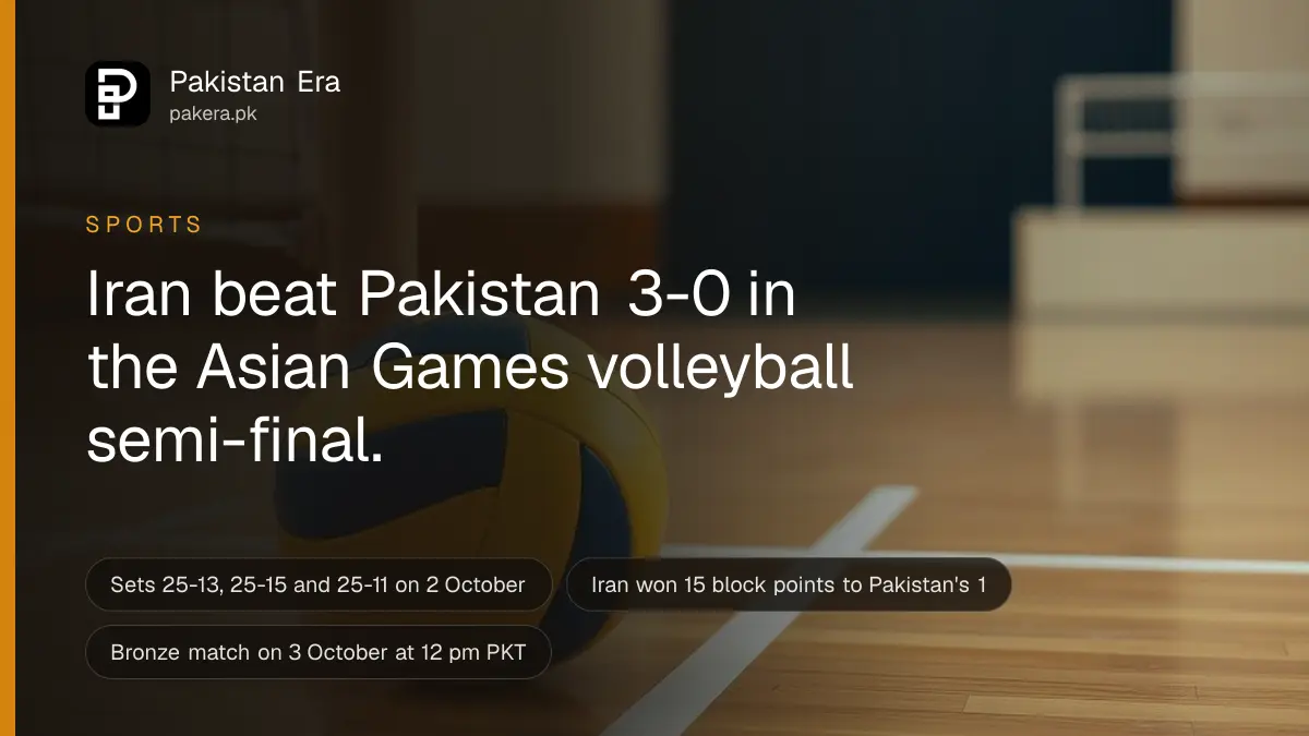 A volleyball rolling slowly across a wooden indoor court floor near the base of a net post under warm hall lights