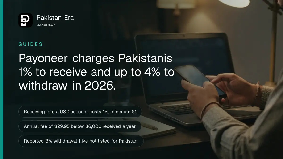 Hands holding a phone over a laptop keyboard at a desk in Lahore while checking payment fees