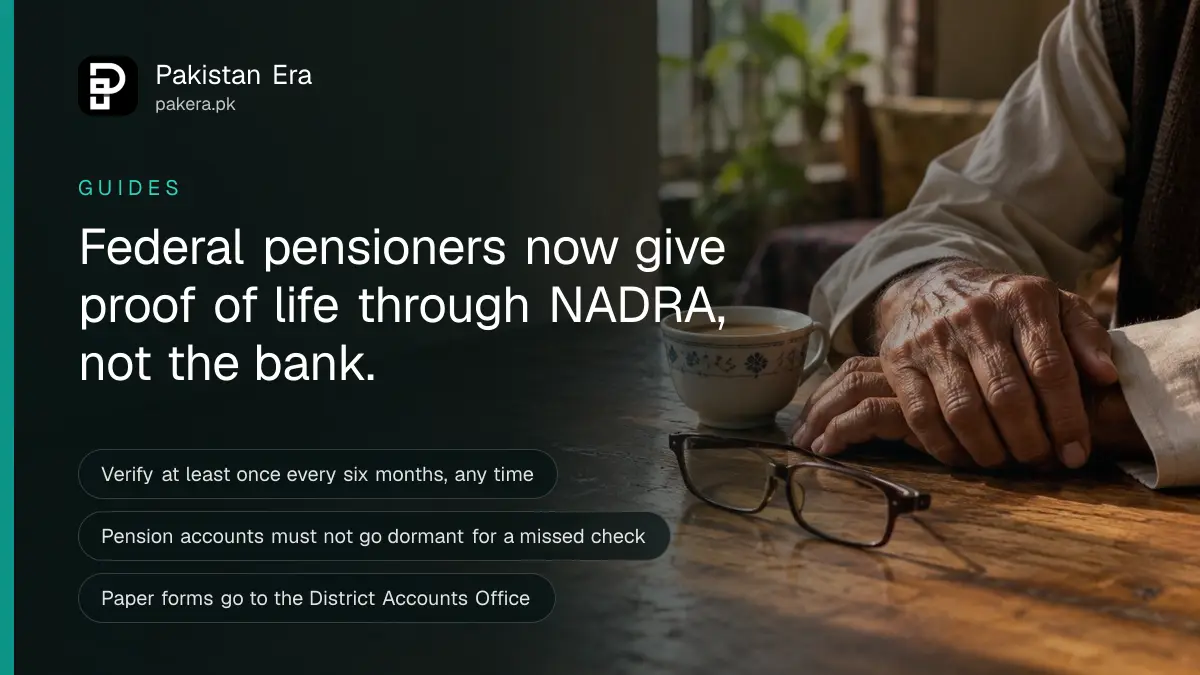 An elderly man's hands resting on a wooden table beside reading glasses and a cup of tea in soft morning light