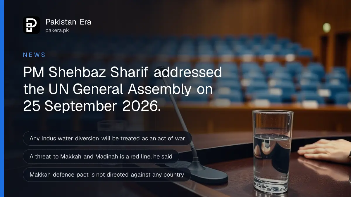 A slim silver microphone and a glass of water on a polished wooden desk in a softly lit conference hall