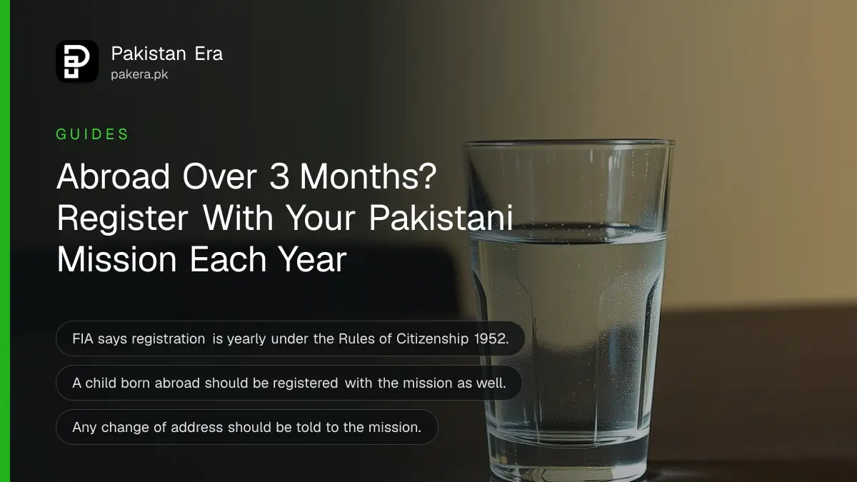 A glass of water on a dark wooden table against a plain cream wall in soft daylight