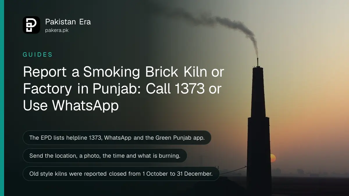 A tall brick kiln chimney with a thin plume of smoke beside a flat field in rural Punjab at dusk