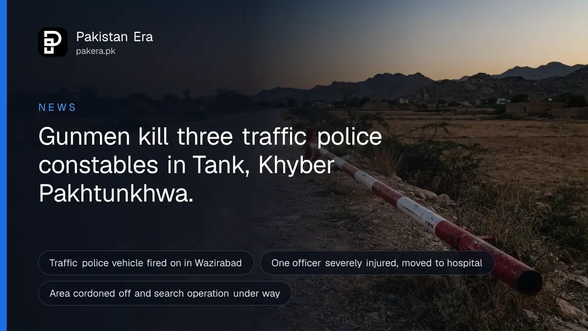 A red and white road barrier pole raised beside an empty rural road in southern Khyber Pakhtunkhwa at dusk, with low brown hills in the distance