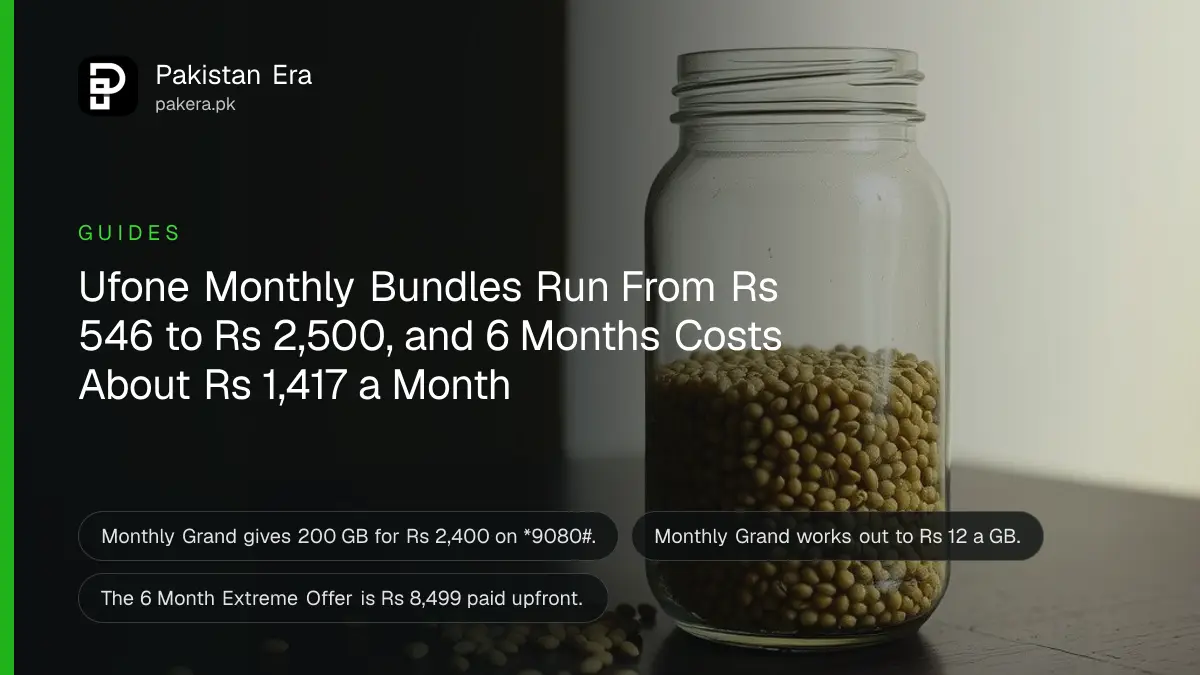 A green glass jar of whole lentils on a dark wooden table against a plain cream wall in soft daylight